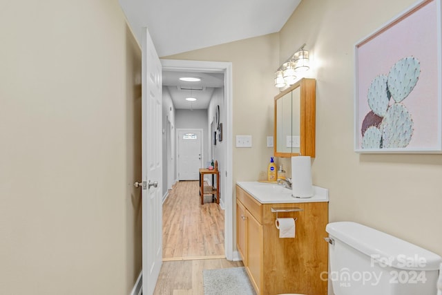 bathroom with vaulted ceiling, vanity, hardwood / wood-style floors, and toilet