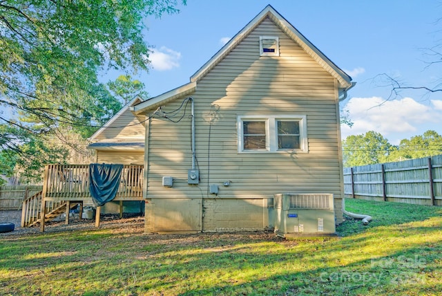 back of house with a wooden deck and a lawn