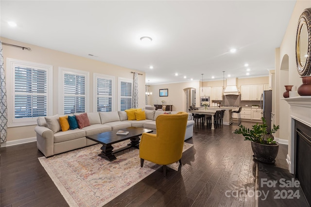 living room featuring ornamental molding, a chandelier, and dark wood-type flooring