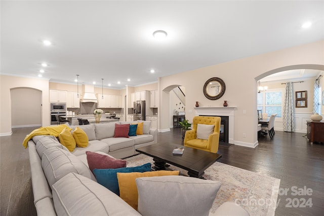 living room with a notable chandelier, crown molding, and dark wood-type flooring