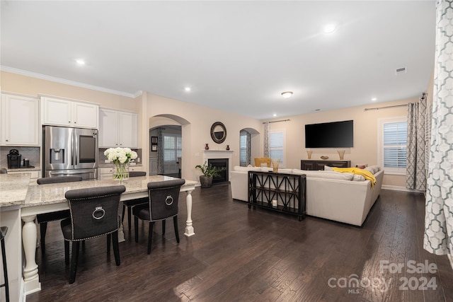 kitchen with white cabinets, stainless steel refrigerator with ice dispenser, a kitchen bar, dark hardwood / wood-style flooring, and light stone countertops