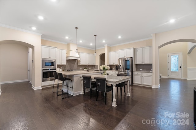 kitchen featuring a kitchen island with sink, white cabinets, dark hardwood / wood-style floors, and decorative light fixtures