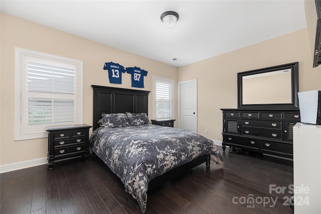 bedroom with multiple windows and dark hardwood / wood-style flooring