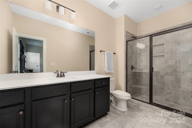 bathroom featuring vanity, toilet, an enclosed shower, and tile patterned floors