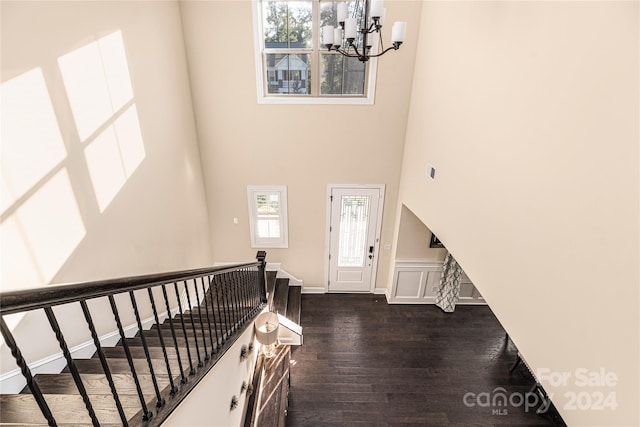 foyer entrance with a towering ceiling, a notable chandelier, and dark hardwood / wood-style floors