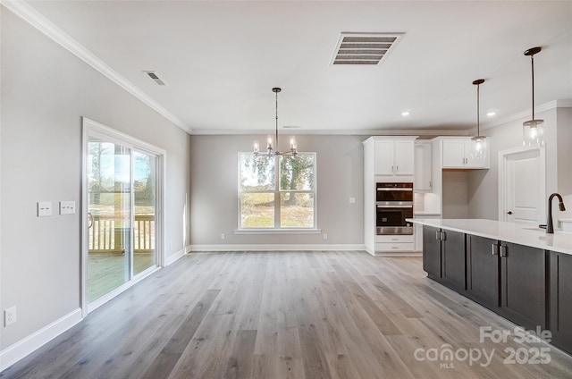 kitchen with white cabinetry, sink, a notable chandelier, double oven, and pendant lighting