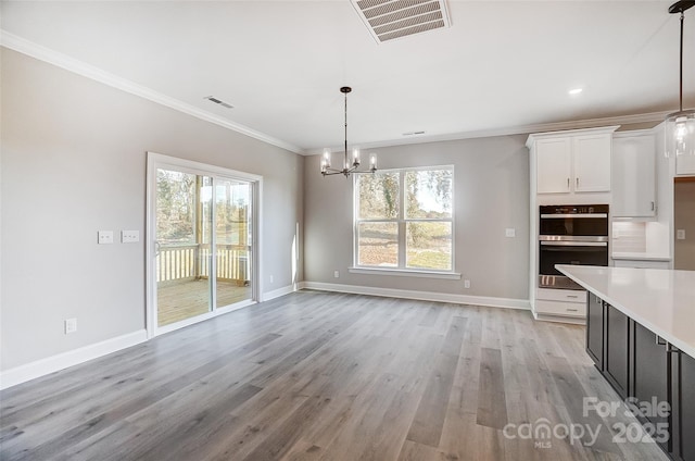 unfurnished dining area with light wood-type flooring, ornamental molding, and a chandelier