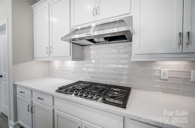 kitchen with white cabinets, stainless steel gas cooktop, extractor fan, and tasteful backsplash