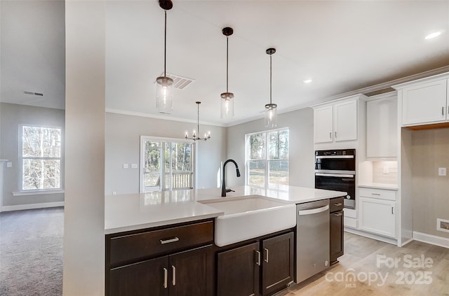 kitchen featuring dishwasher, sink, white cabinets, and hanging light fixtures