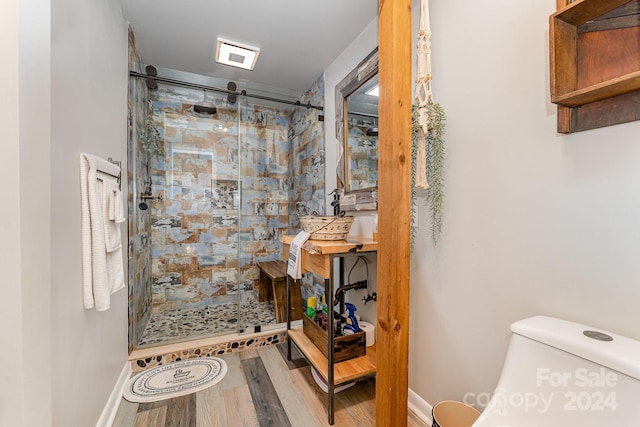 bathroom with hardwood / wood-style floors, toilet, and an enclosed shower