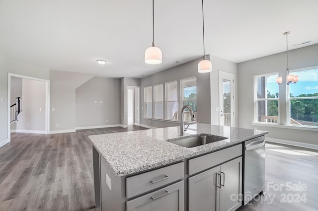 kitchen with sink, hanging light fixtures, hardwood / wood-style flooring, an inviting chandelier, and a center island with sink