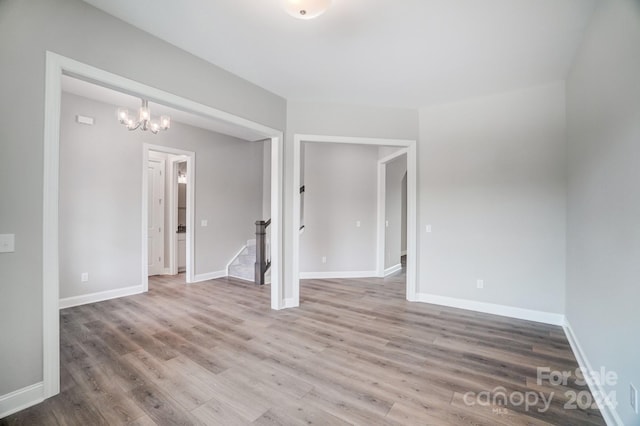 spare room featuring an inviting chandelier and wood-type flooring