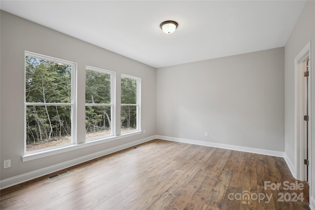 empty room featuring a healthy amount of sunlight and hardwood / wood-style floors