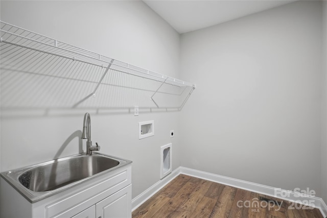 clothes washing area featuring cabinet space, baseboards, dark wood-style flooring, hookup for an electric dryer, and a sink