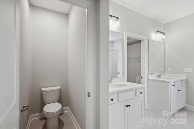 bathroom featuring two vanities, a sink, toilet, and tile patterned floors