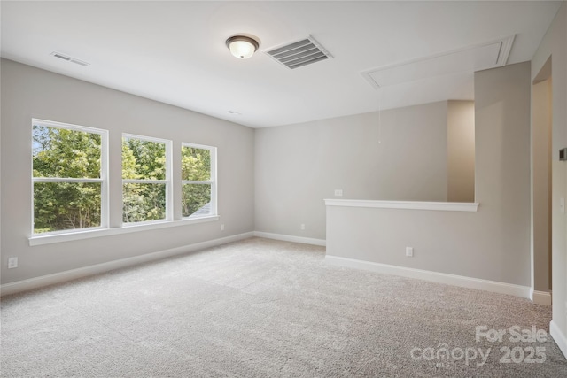 empty room with visible vents, light carpet, attic access, and baseboards