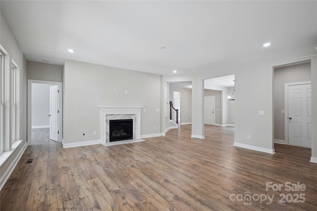 unfurnished living room with recessed lighting, a fireplace, baseboards, and wood finished floors