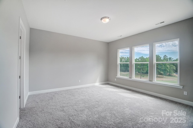 spare room featuring carpet floors, baseboards, and visible vents