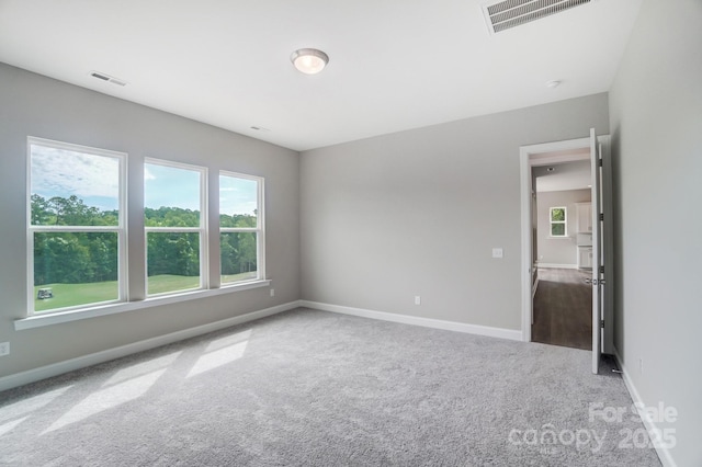 carpeted empty room featuring baseboards and visible vents