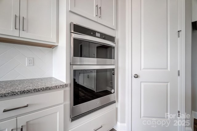552 Fern Hill Rd Unit 21, Mooresville, NC 28117 - kitchen with tasteful backsplash, stainless steel double oven, white cabinets, light stone countertops, and baseboards