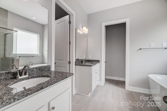 552 Fern Hill Rd Unit 21, Mooresville, NC 28117 - bathroom featuring a freestanding tub, baseboards, a shower stall, and two vanities