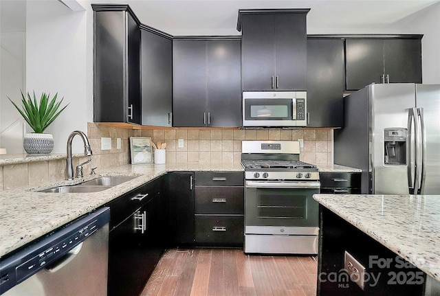 kitchen with dark wood-type flooring, stainless steel appliances, light stone counters, and sink