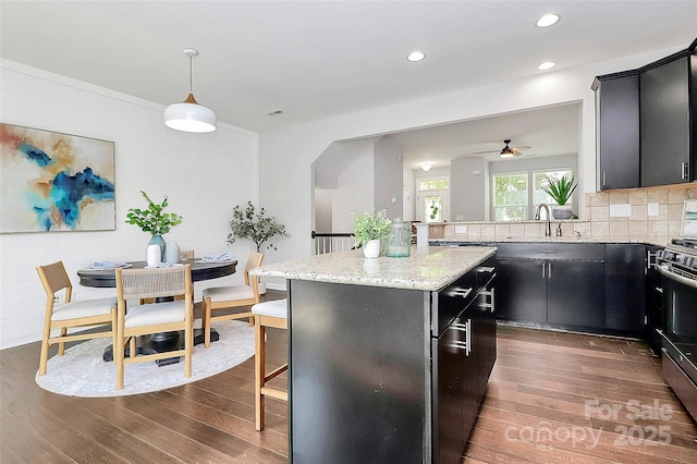 kitchen with ceiling fan, tasteful backsplash, dark wood-type flooring, hanging light fixtures, and a center island