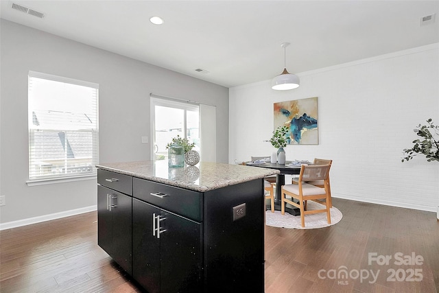 kitchen featuring dark wood-type flooring, pendant lighting, a center island, and a wealth of natural light