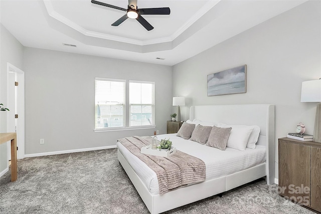 bedroom with ceiling fan, a tray ceiling, and carpet flooring