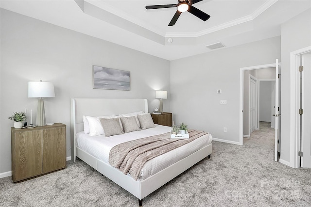 carpeted bedroom featuring ceiling fan, a tray ceiling, and ornamental molding