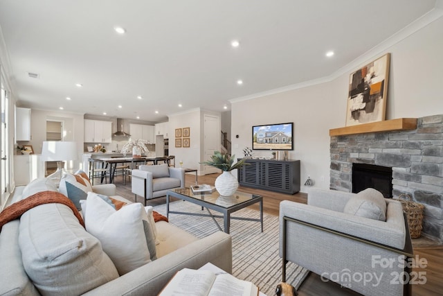 living room featuring light wood-type flooring, crown molding, and a fireplace