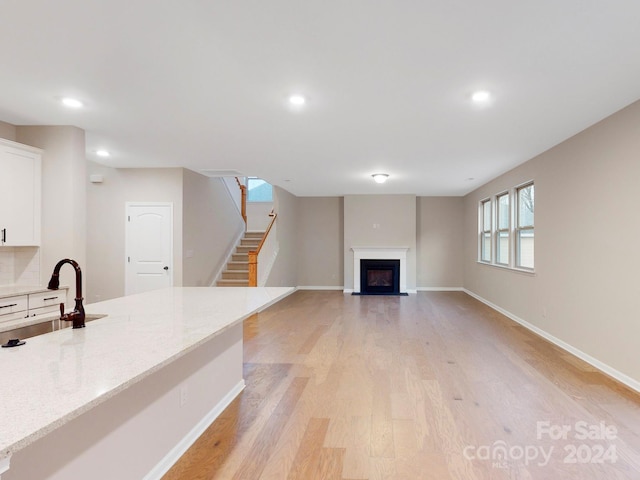 unfurnished living room with light hardwood / wood-style floors and sink