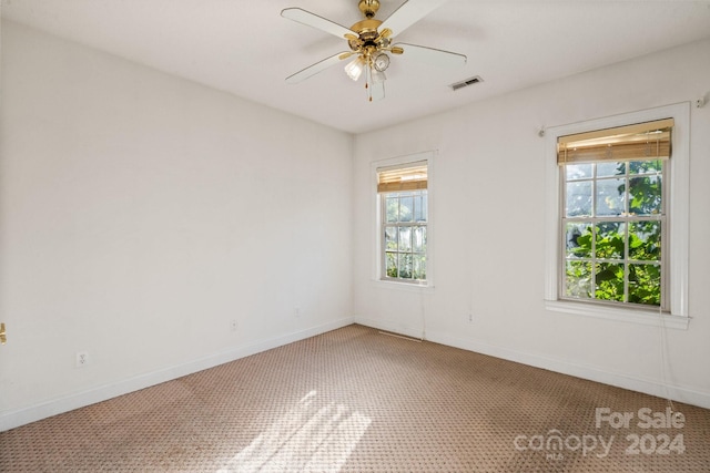 unfurnished room featuring light colored carpet, a ceiling fan, a healthy amount of sunlight, and visible vents