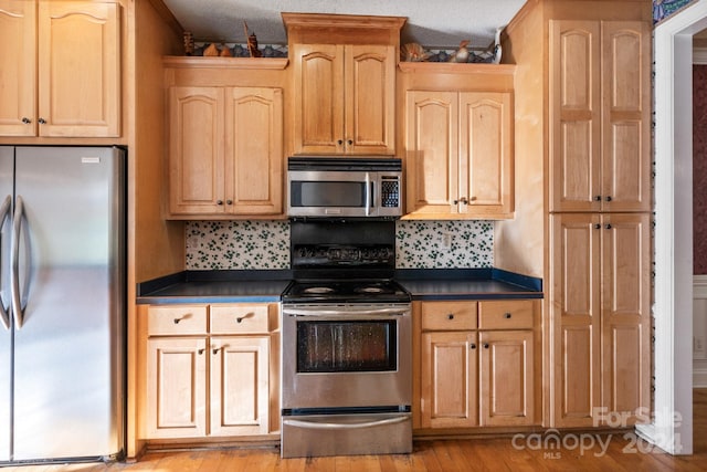 kitchen featuring a textured ceiling, stainless steel appliances, light hardwood / wood-style floors, and decorative backsplash