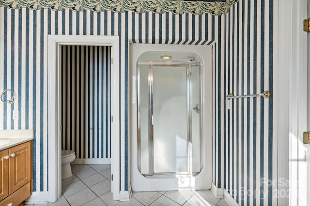 bathroom featuring tile patterned flooring, vanity, toilet, and an enclosed shower