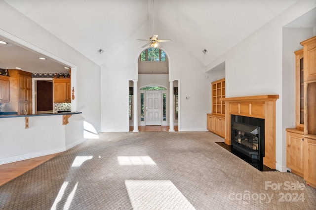 unfurnished living room featuring ceiling fan, light colored carpet, and high vaulted ceiling