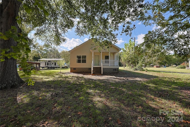 rear view of house featuring a lawn and a porch