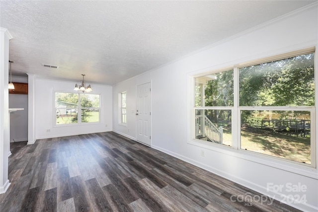 unfurnished living room with a textured ceiling, ornamental molding, dark wood-type flooring, and a notable chandelier