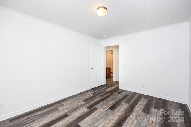 spare room featuring a textured ceiling, ornamental molding, and dark wood-type flooring