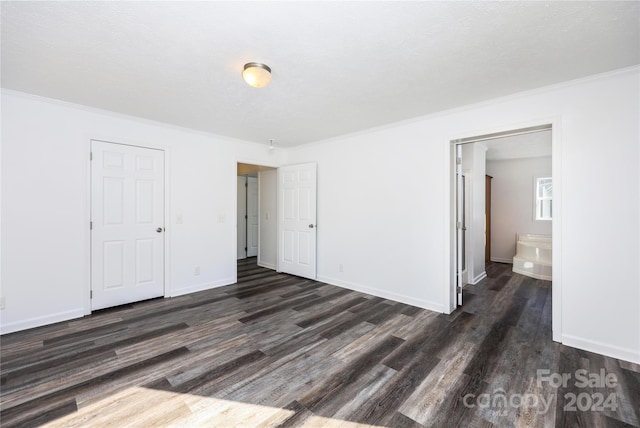 unfurnished bedroom featuring crown molding, connected bathroom, and dark wood-type flooring