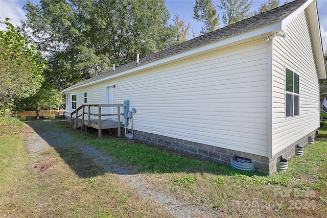 view of side of home with a wooden deck and a yard