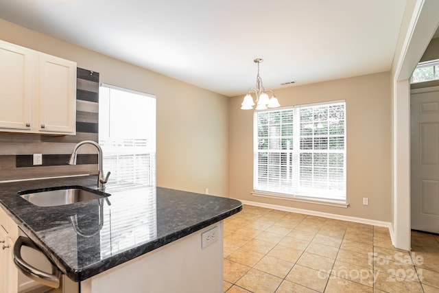 kitchen with dark stone counters, hanging light fixtures, white cabinetry, and sink