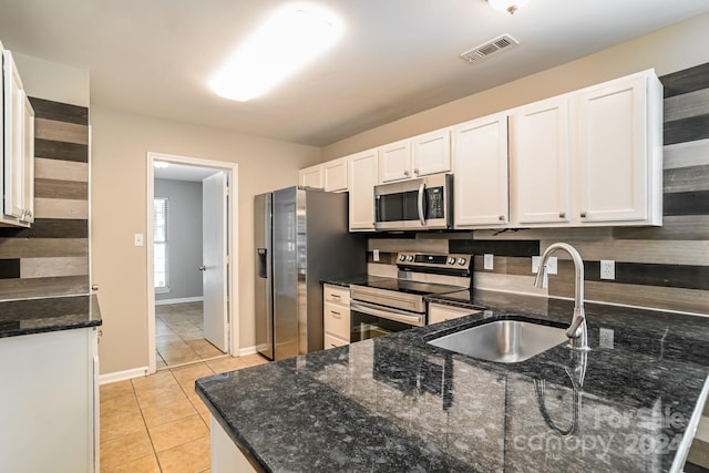 kitchen featuring dark stone counters, white cabinetry, appliances with stainless steel finishes, decorative backsplash, and sink