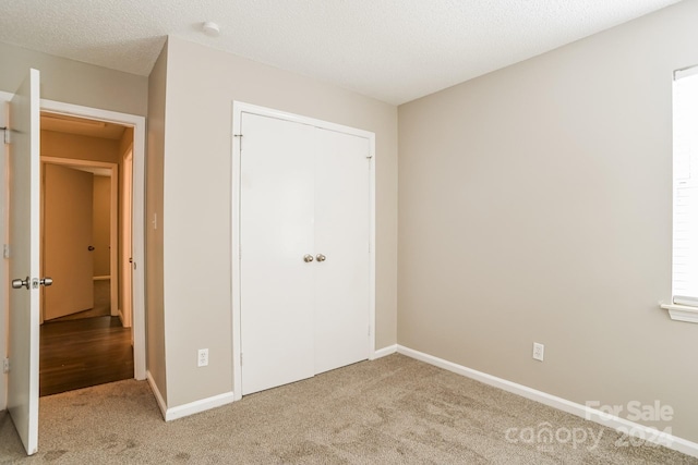 unfurnished bedroom featuring a closet, a textured ceiling, and carpet floors