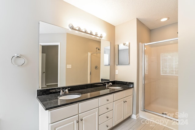 bathroom with walk in shower, vanity, and a textured ceiling