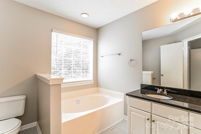 bathroom featuring a bathing tub, vanity, a textured ceiling, and toilet