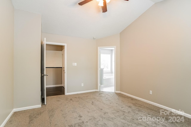 unfurnished bedroom with lofted ceiling, carpet flooring, ceiling fan, and ensuite bathroom