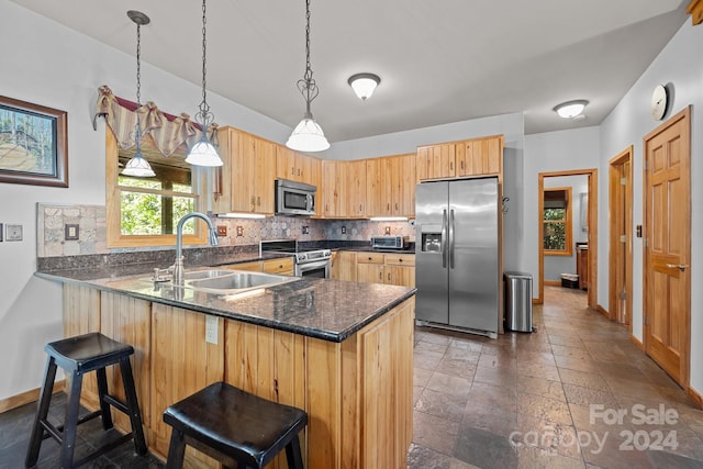 kitchen with sink, backsplash, hanging light fixtures, stainless steel appliances, and a breakfast bar area