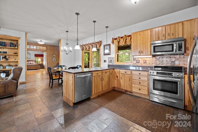 kitchen featuring kitchen peninsula, stainless steel appliances, backsplash, sink, and pendant lighting