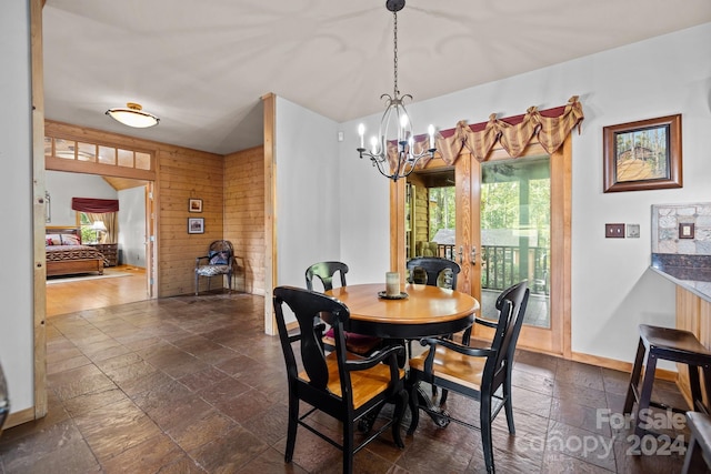 dining room with wooden walls and a notable chandelier